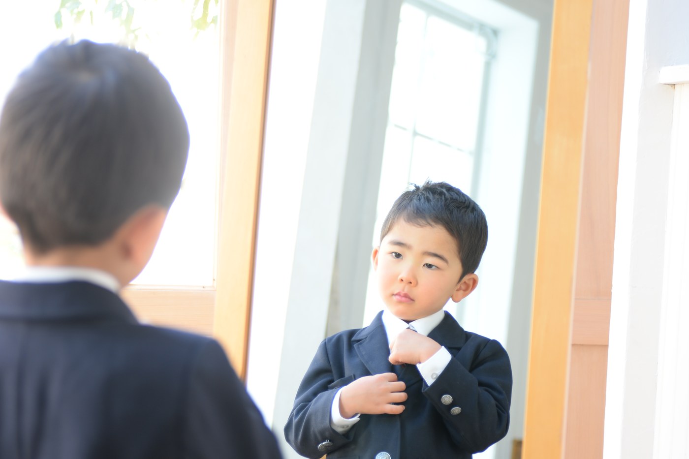 姿見の前でネクタイを整える園児