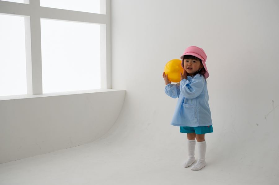 スモックを着てボールで遊ぶ女の子