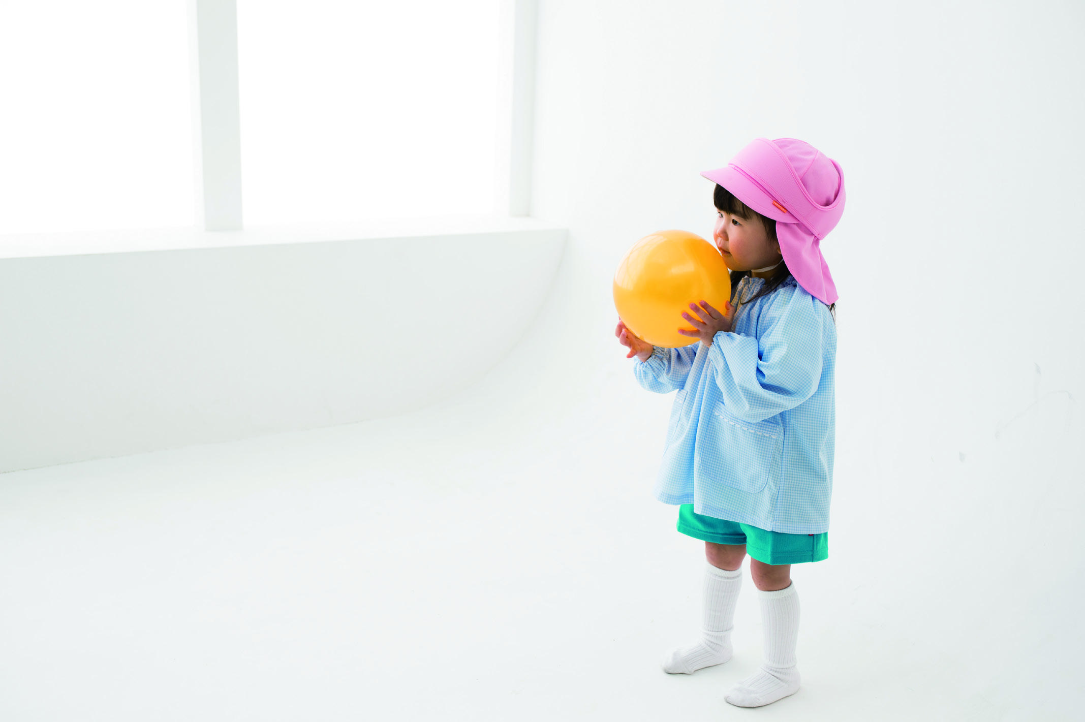 ピンクのまもる君をかぶり、黄色いボールを抱える子ども